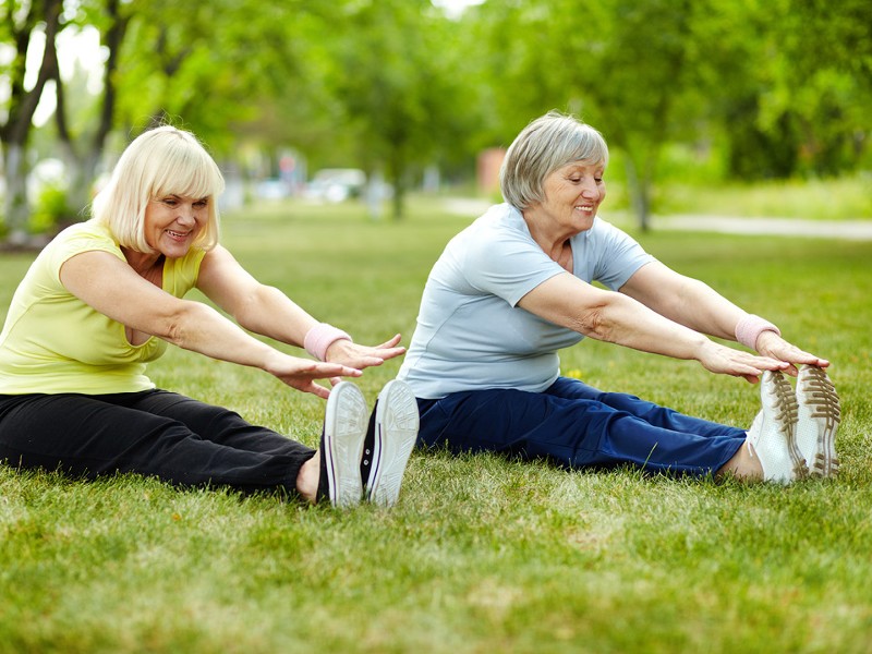 2 Frauen sitzen im Gras und dehnen sich. © shutterstock Inc. 