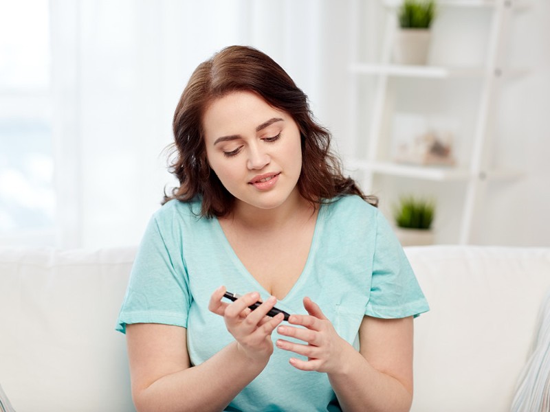 Frau in hellblauem T-Shirt misst Blutzucker mit Pen. © shutterstock Inc. 