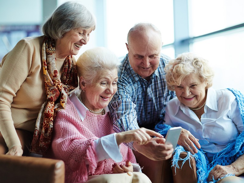 3 Frauen und 1 Mann sehen sich etwas am Smartphone an, © Shutterstock Inc.