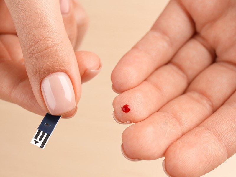 Finger mit Blutstropfen, in der anderen Hand Teststreifen. © shutterstock Inc. 