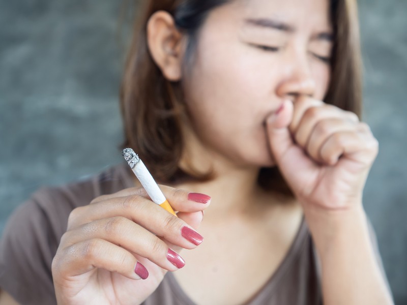 Frau mit rauchender Zigarette, die hustet; Foto: Doucefleur/Shutterstock.com